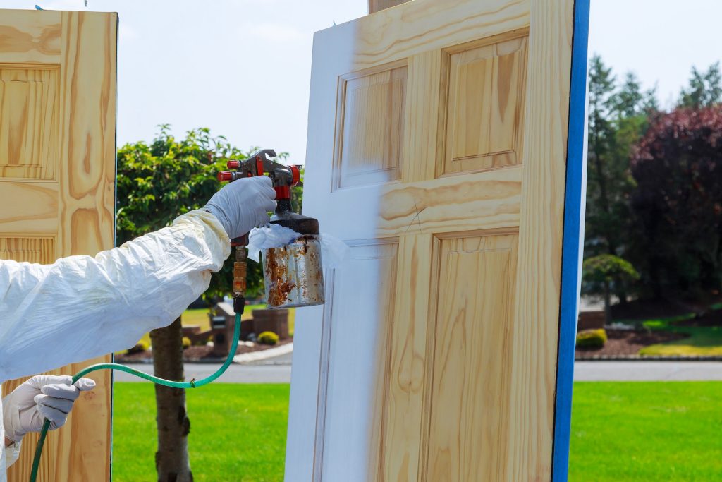 Close-up of master painting spray gun wood doors.
