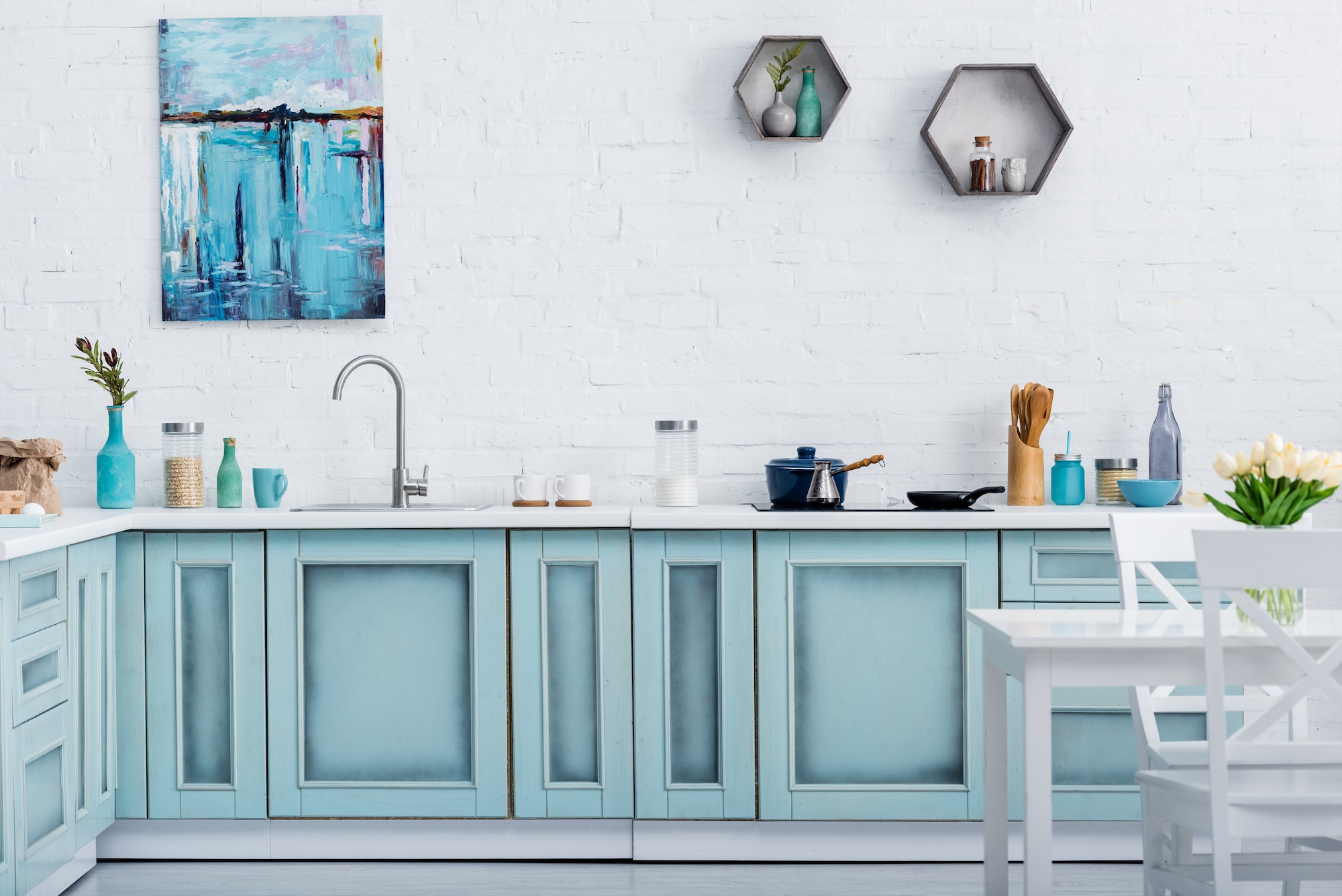 interior of modern turquoise kitchen with painting on white brick wall